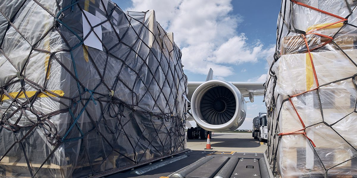 Preparation before flight. Loading of cargo containers against jet engine of freight airplane.